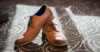 Чоловічі шкіряні туфлі коричневого кольору стоять на килимі.