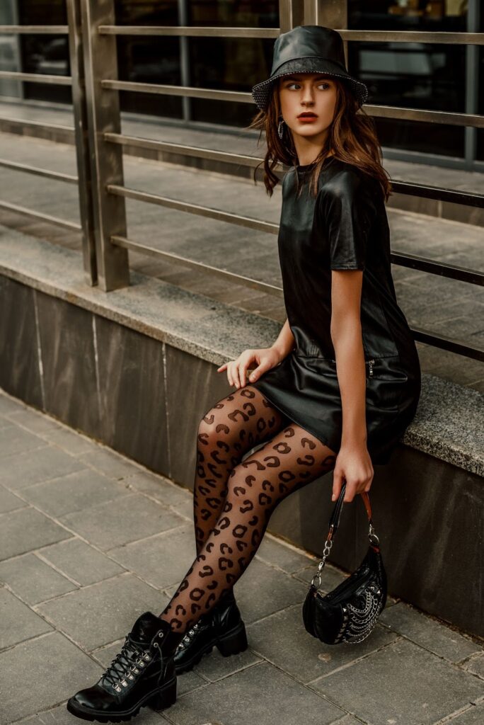 Дівчина сидить у чорній стилізації з колготками з леопардовим принтом чорного кольору.