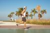 Młody mężczyzna uprawiający jogging w męskich butach sportowych, w tle palmy i plaża Молодий чоловік, робить пробіжку у чоловічому спортивному взутті серед пальм та на пляжі